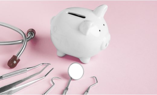 A piggy bank and dental impliments on a light pink background.